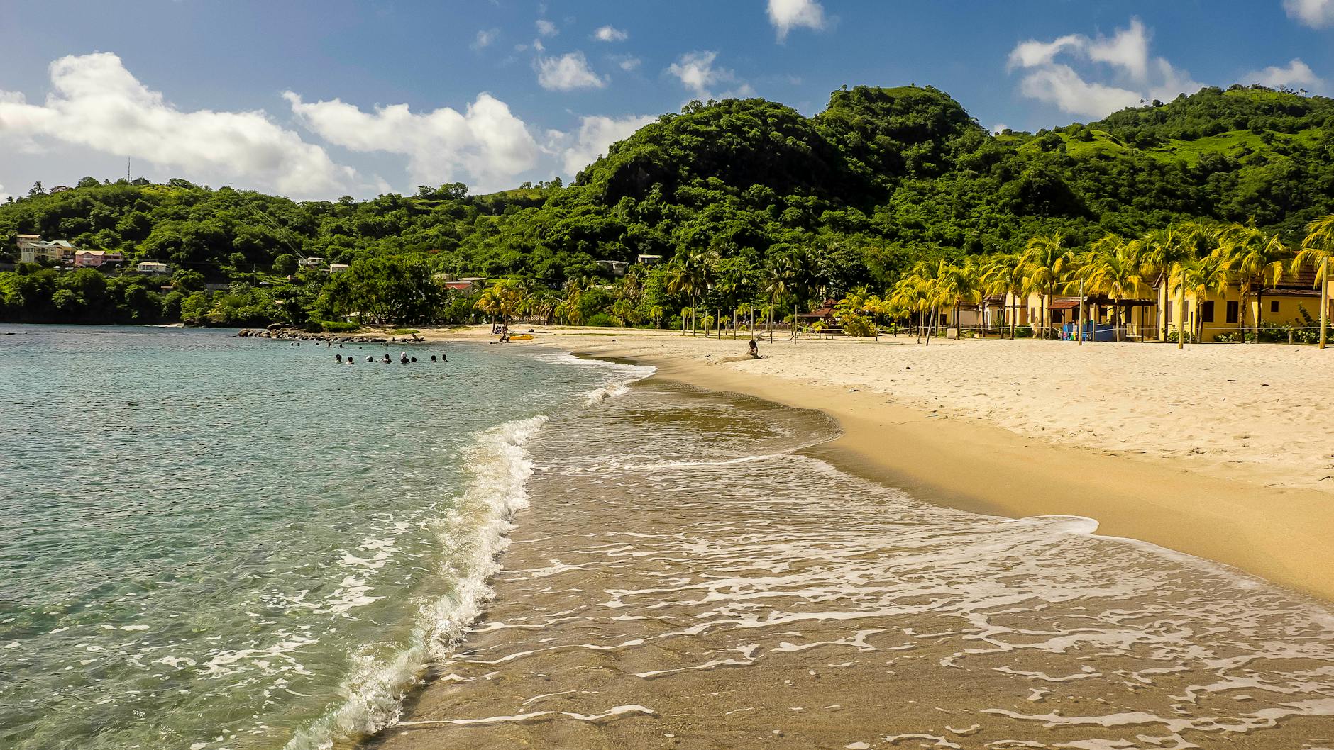 Beach scene in Buccament Bay, Saint Vincent, with villas backed by lush green hills