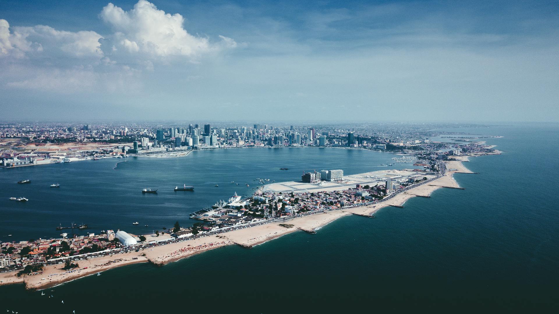 Aerial view of Luanda's Atlantic coastline and modern skyline under a clear blue sky, Angola