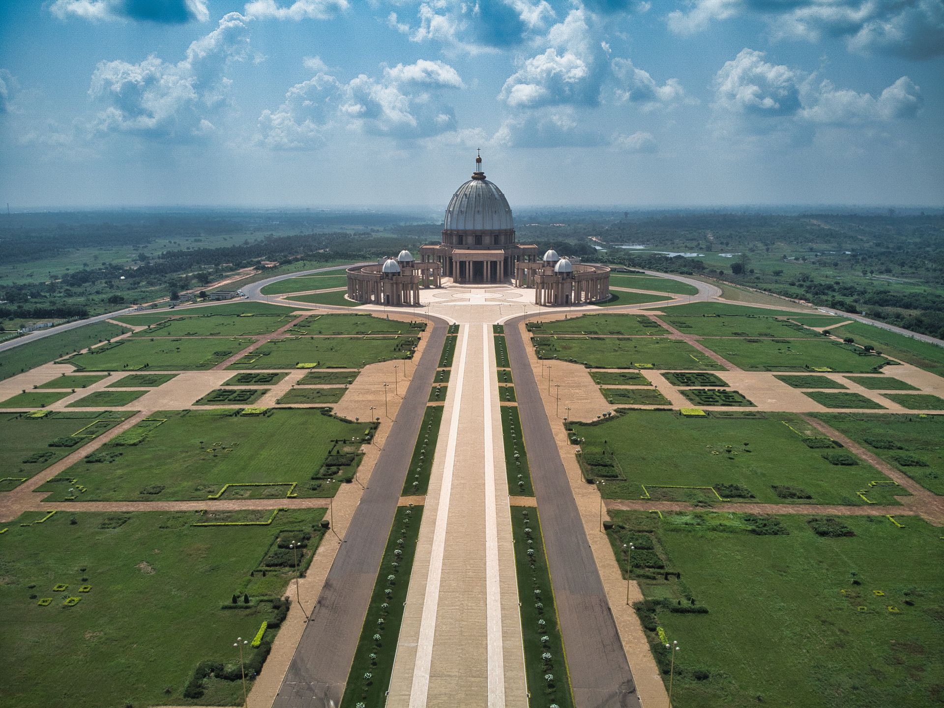 Aerial drone view of the white-domed Basilica of Our Lady of Peace surrounded by lawns and palm trees in Yamoussoukro, C&ocirc;te d&rsquo;Ivoire