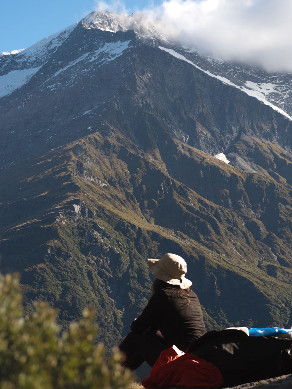 Hiker resting above a Southern Alps view near Wānaka — the kind of ridgeline day Roys Peak delivers