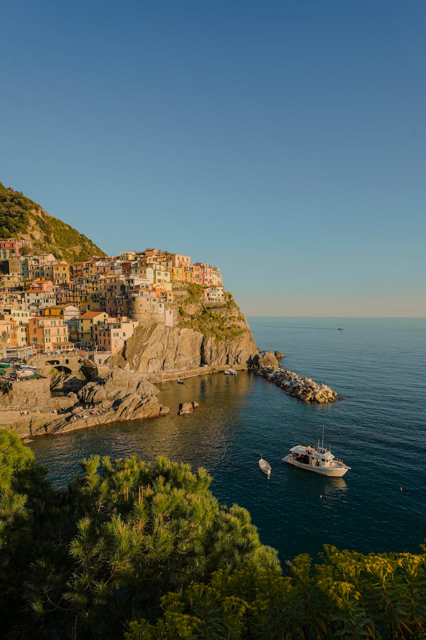 Coastal village of Manarola in Cinque Terre with colourful houses and boats on the sea on a sunny day