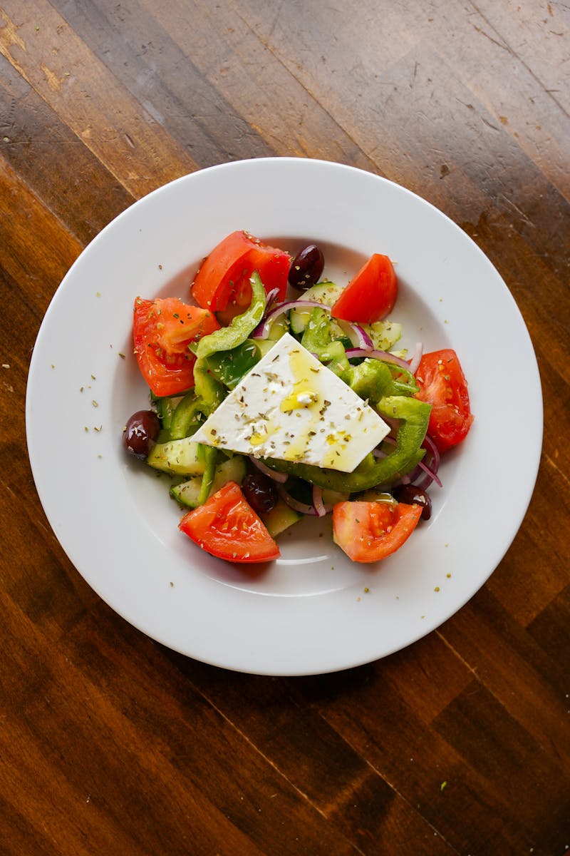 Traditional horiatiki Greek salad with feta, tomato, cucumber and olives on a white plate