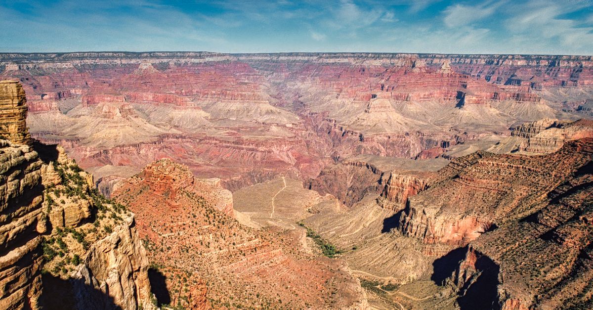 Layered red rock walls of the Grand Canyon falling away to the Colorado River far below