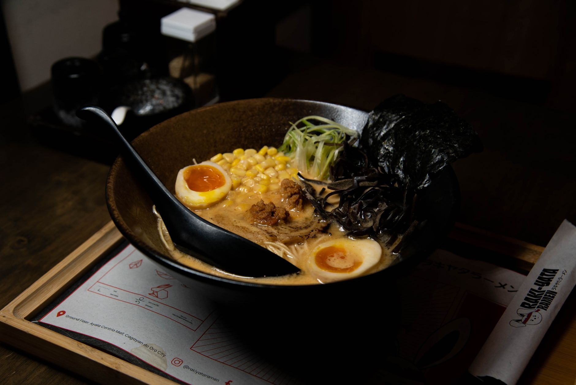 Close-up of a steaming ramen bowl with egg, seaweed and toppings