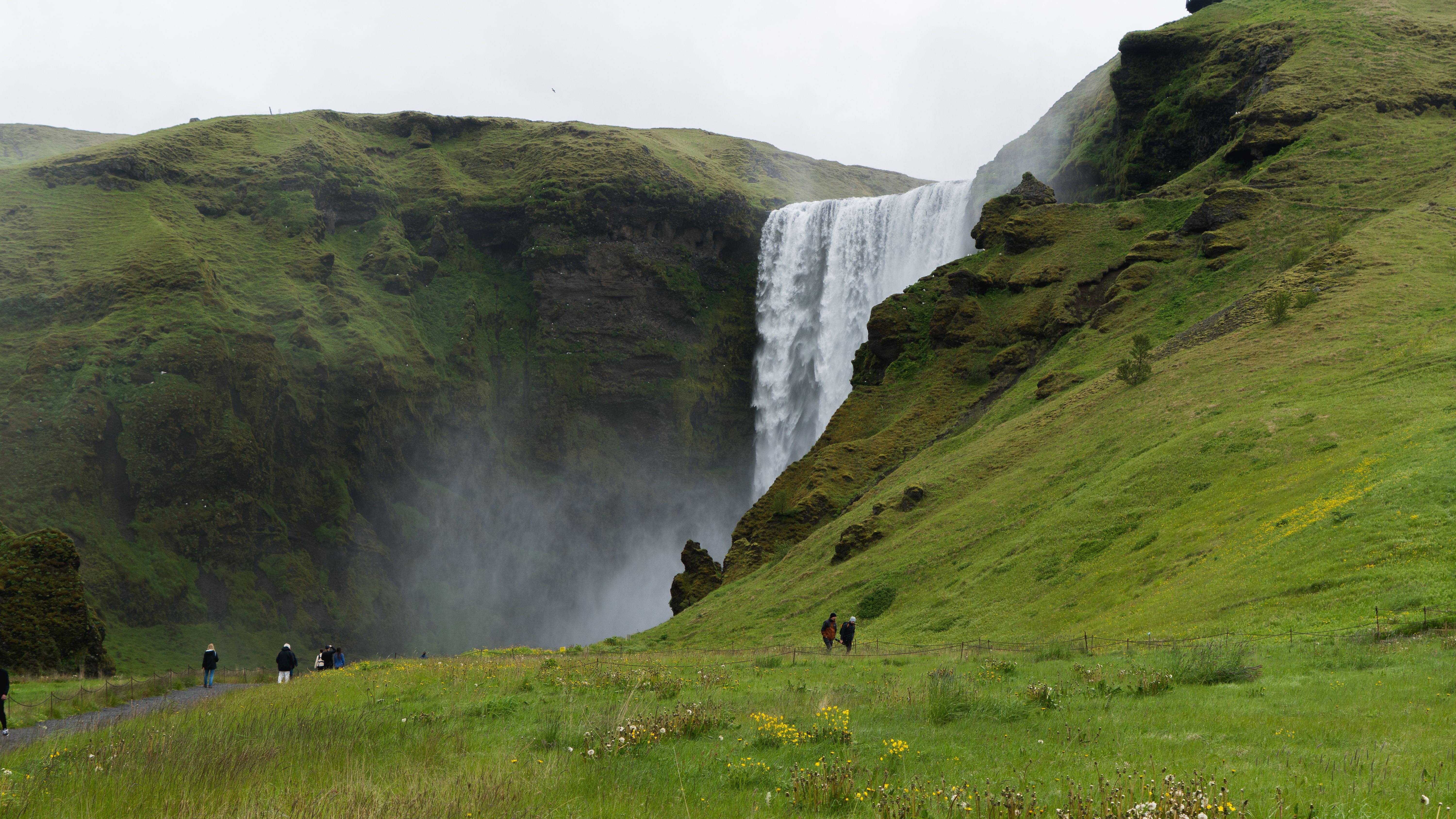 Skógafoss waterfall on Iceland's South Coast, a wide curtain of water below green cliffs
