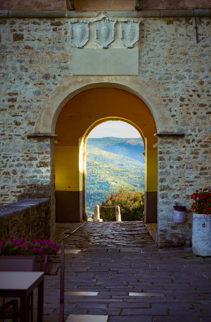 Arched stone passageway overlooking lush hills in Motovun, Istria