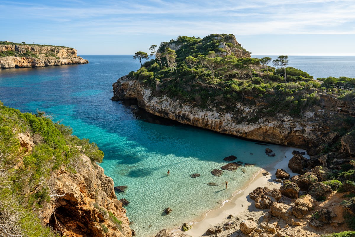 Coastal bay with clear turquoise water and lush greenery on the Mallorca shore