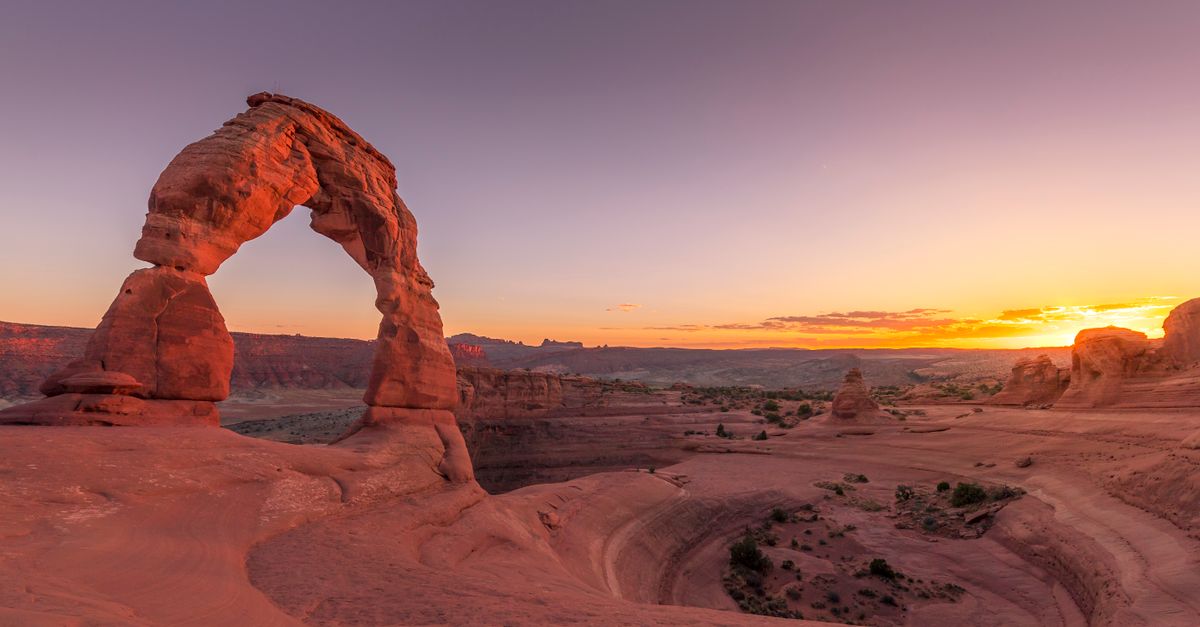 Delicate Arch standing alone on red slickrock at sunset in Arches National Park near Moab