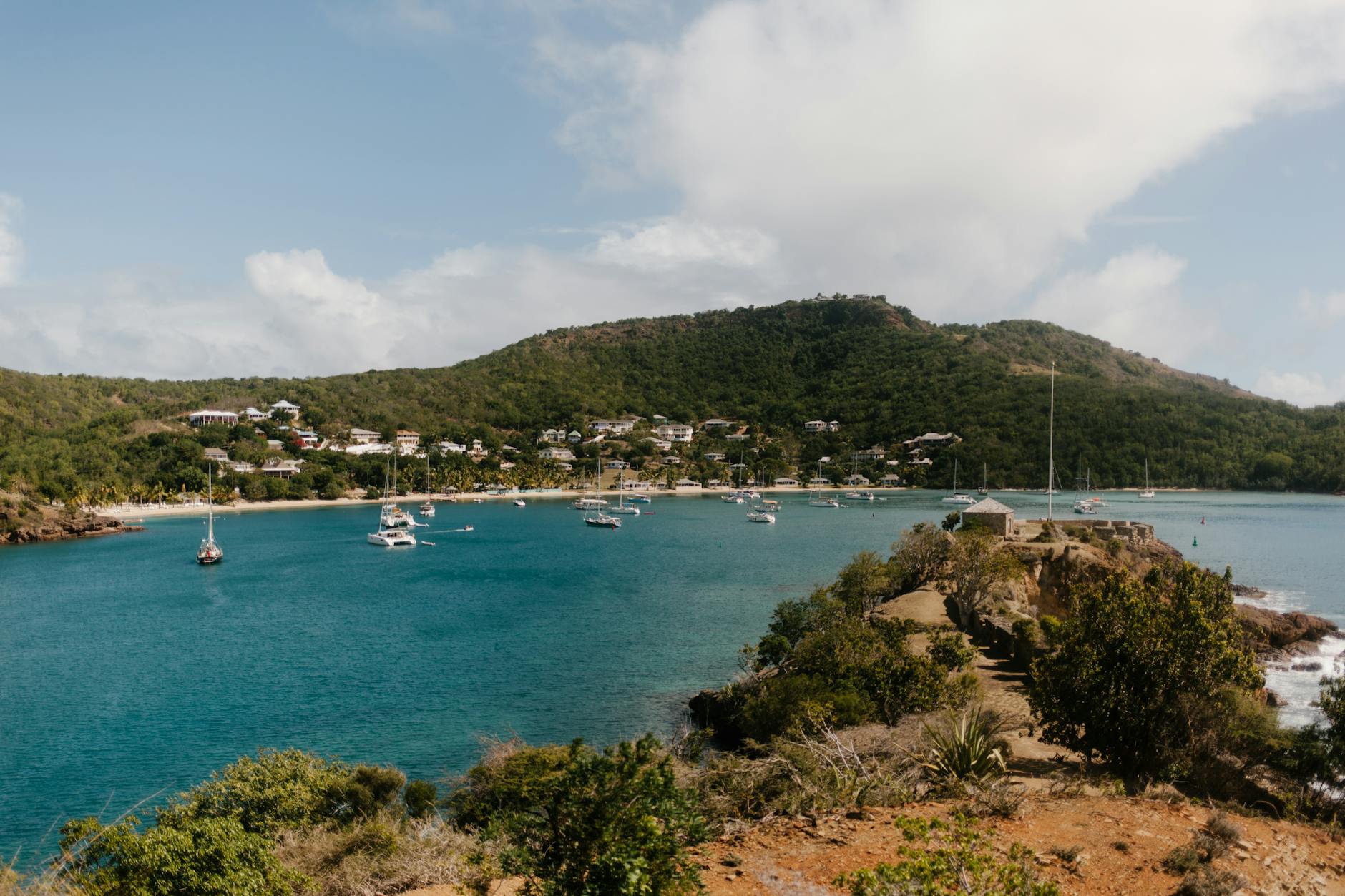 Sailboats anchored in a picturesque bay surrounded by lush green island landscape in the Grenadines