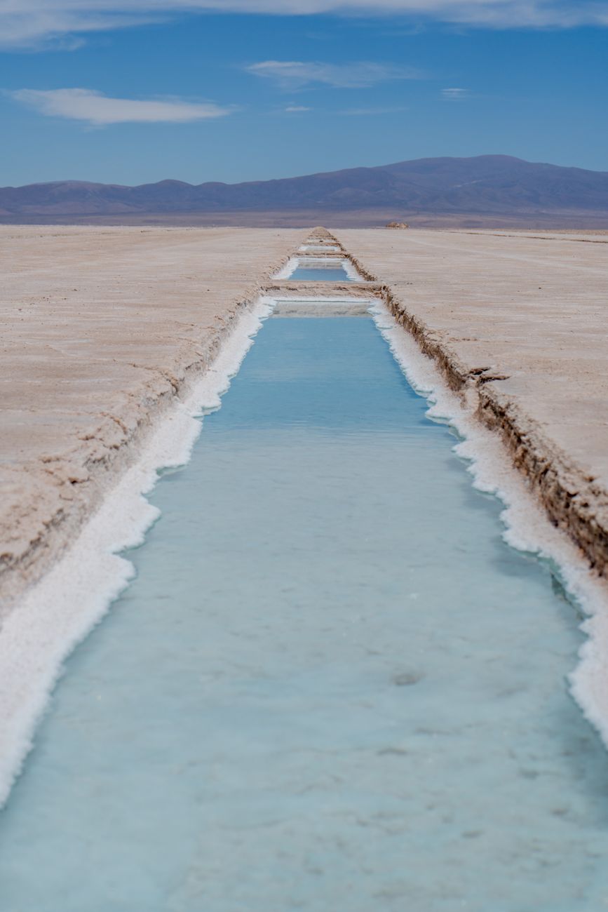 The white crust of Salinas Grandes salt flats stretching to distant hills in Jujuy