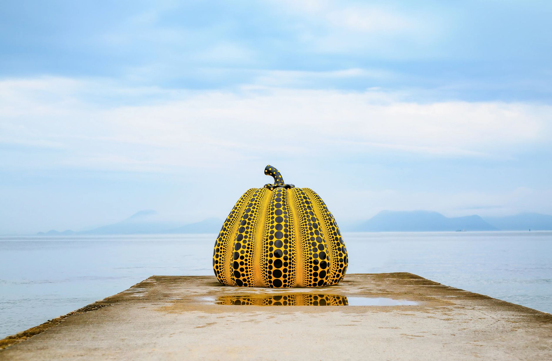 Yellow Yayoi Kusama pumpkin sculpture at the end of a pier on Naoshima, Seto Inland Sea