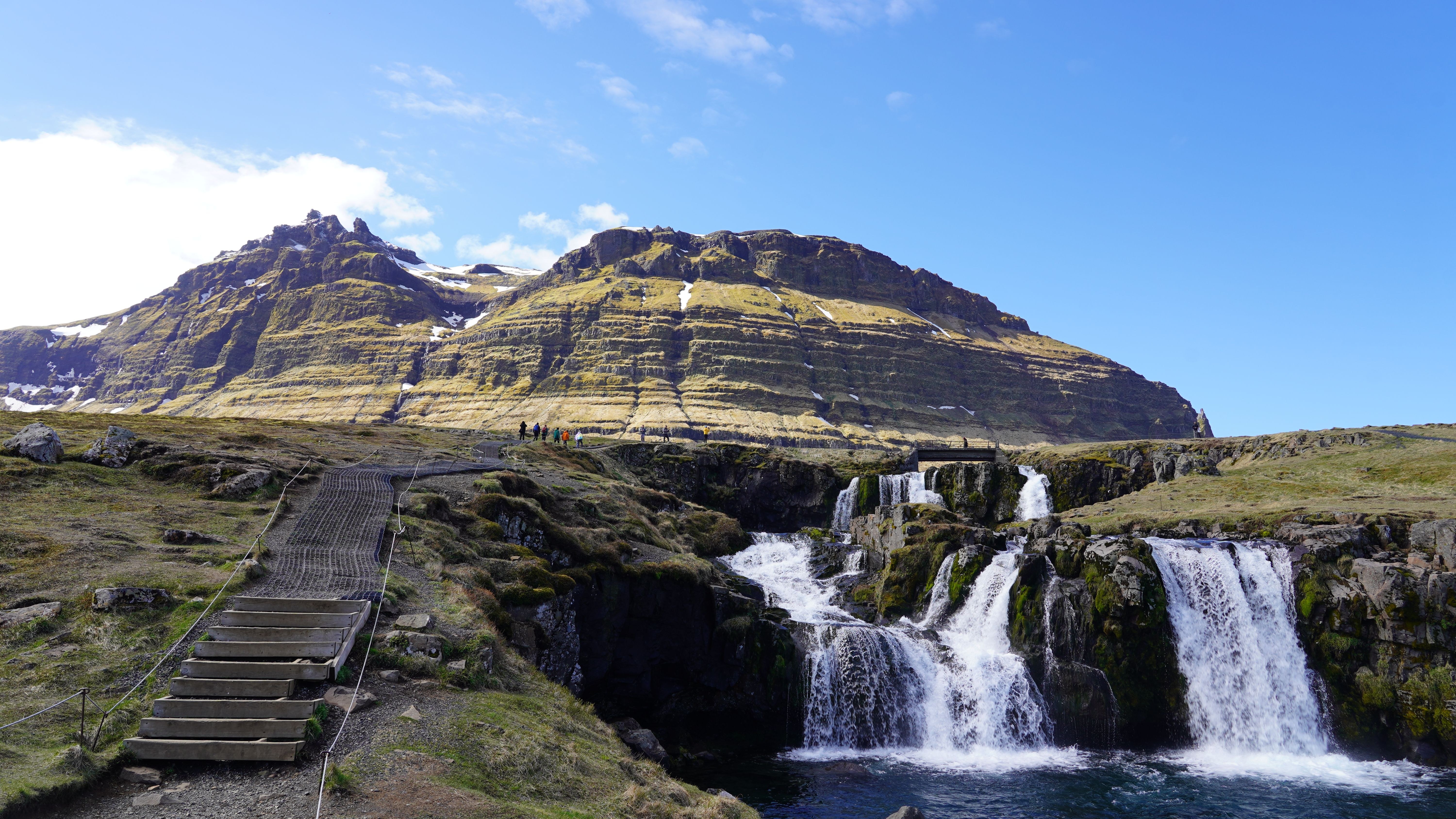 Kirkjufell mountain and its small waterfall on the Snæfellsnes peninsula with the sea beyond