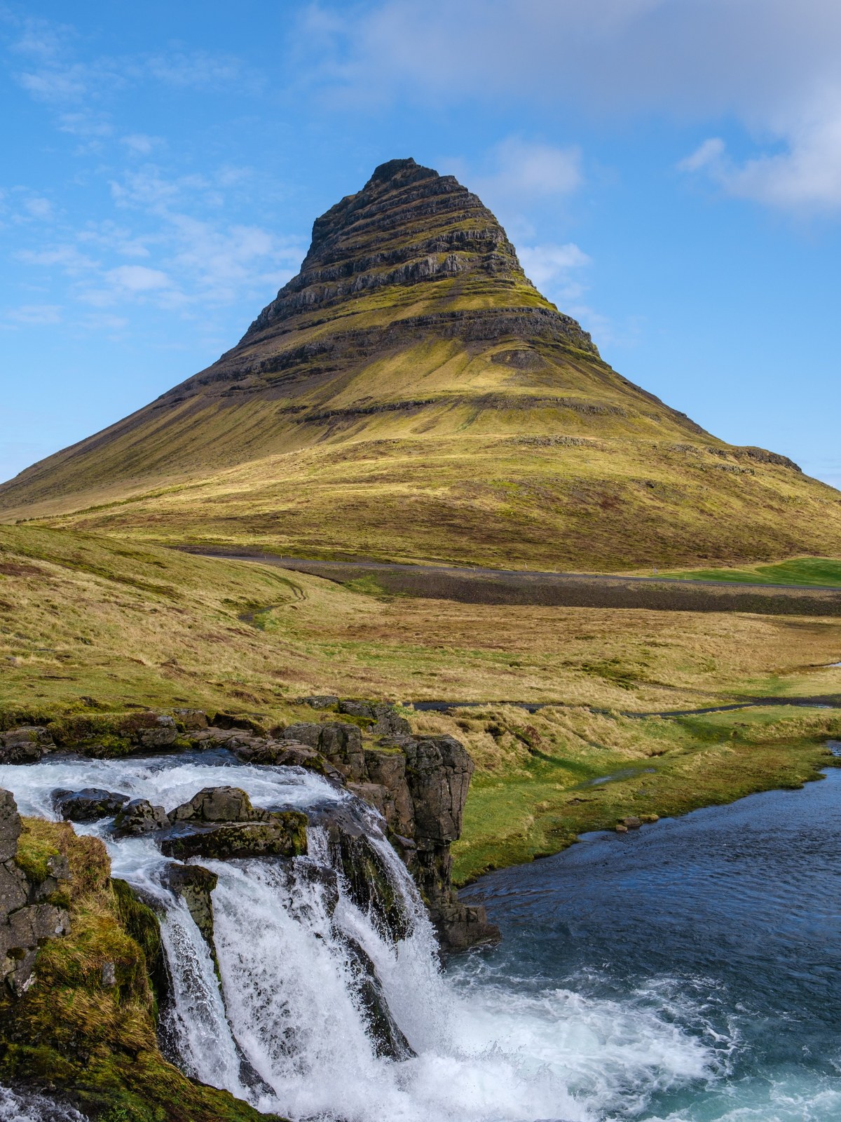 The pointed Kirkjufell mountain beside its waterfall near Grundarfjörður