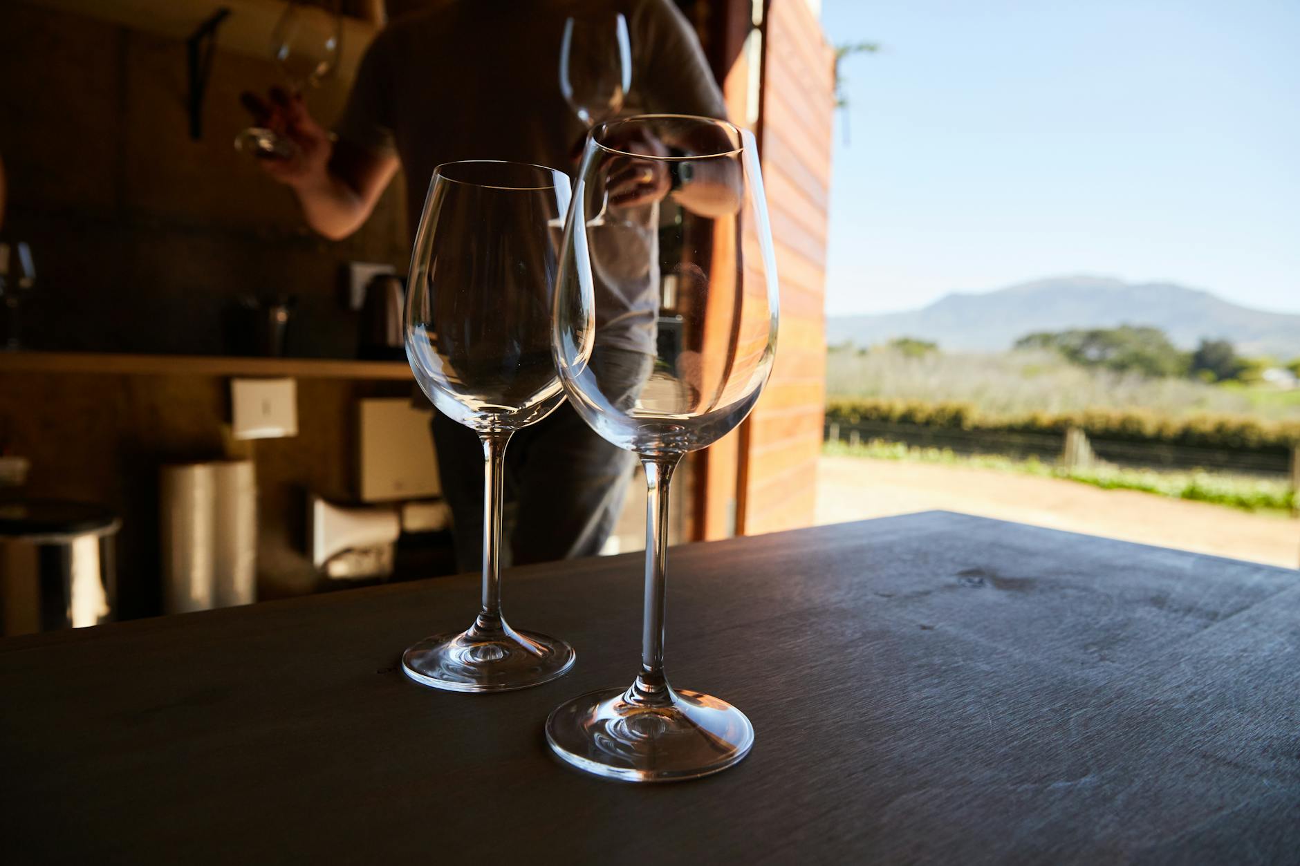 Close-up of wine glasses with a vineyard and mountains in the background