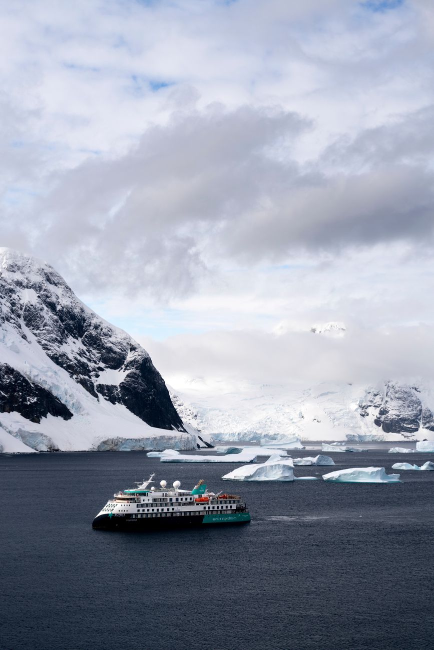 Small expedition ship near icebergs on the route south from Ushuaia