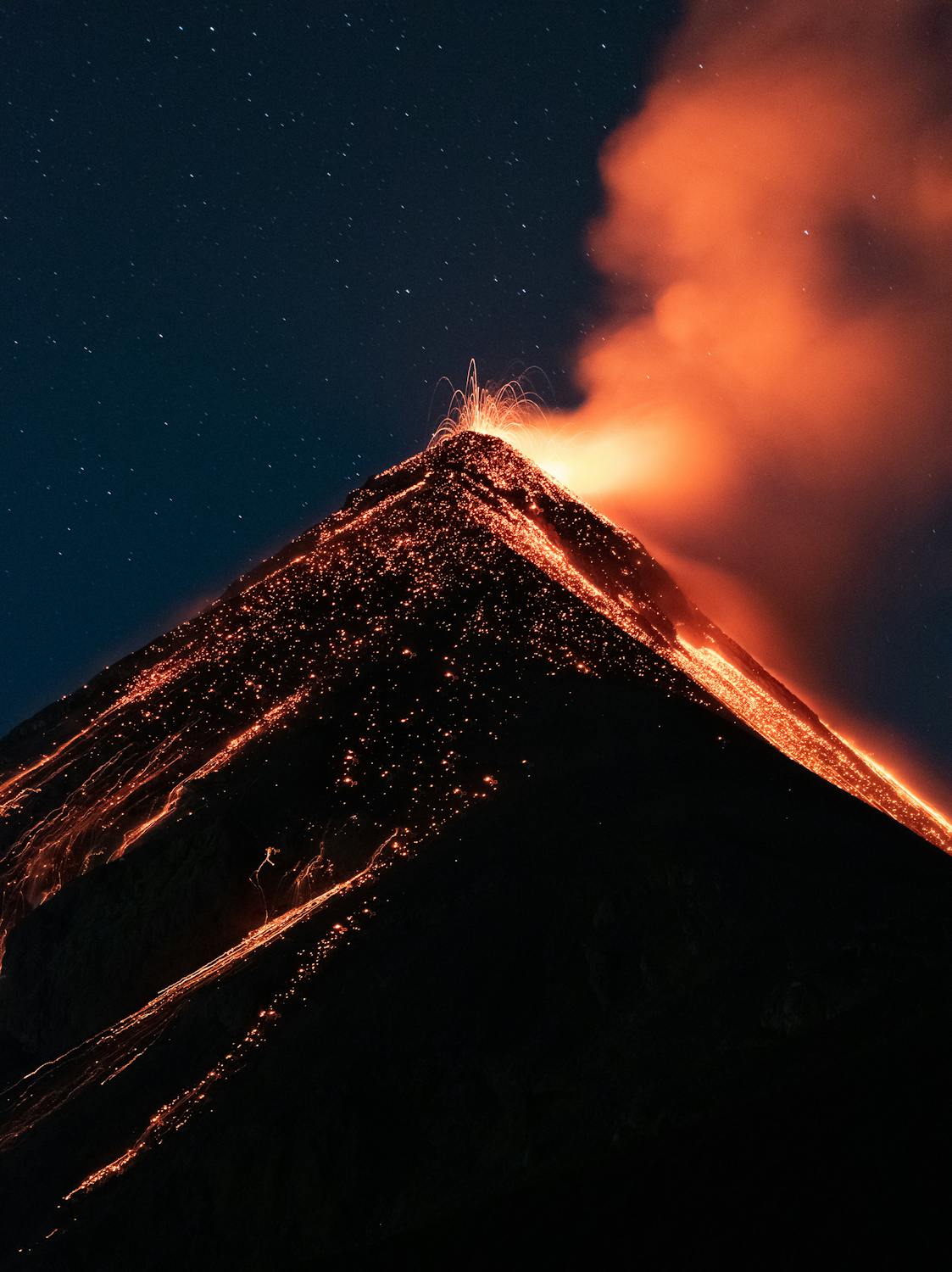 Volcanic eruption at night with glowing lava and smoke under a starry sky, Vanuatu