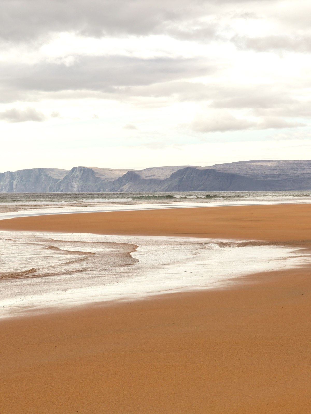 The red-gold sand of Rauðisandur beach stretching along the Westfjords coast