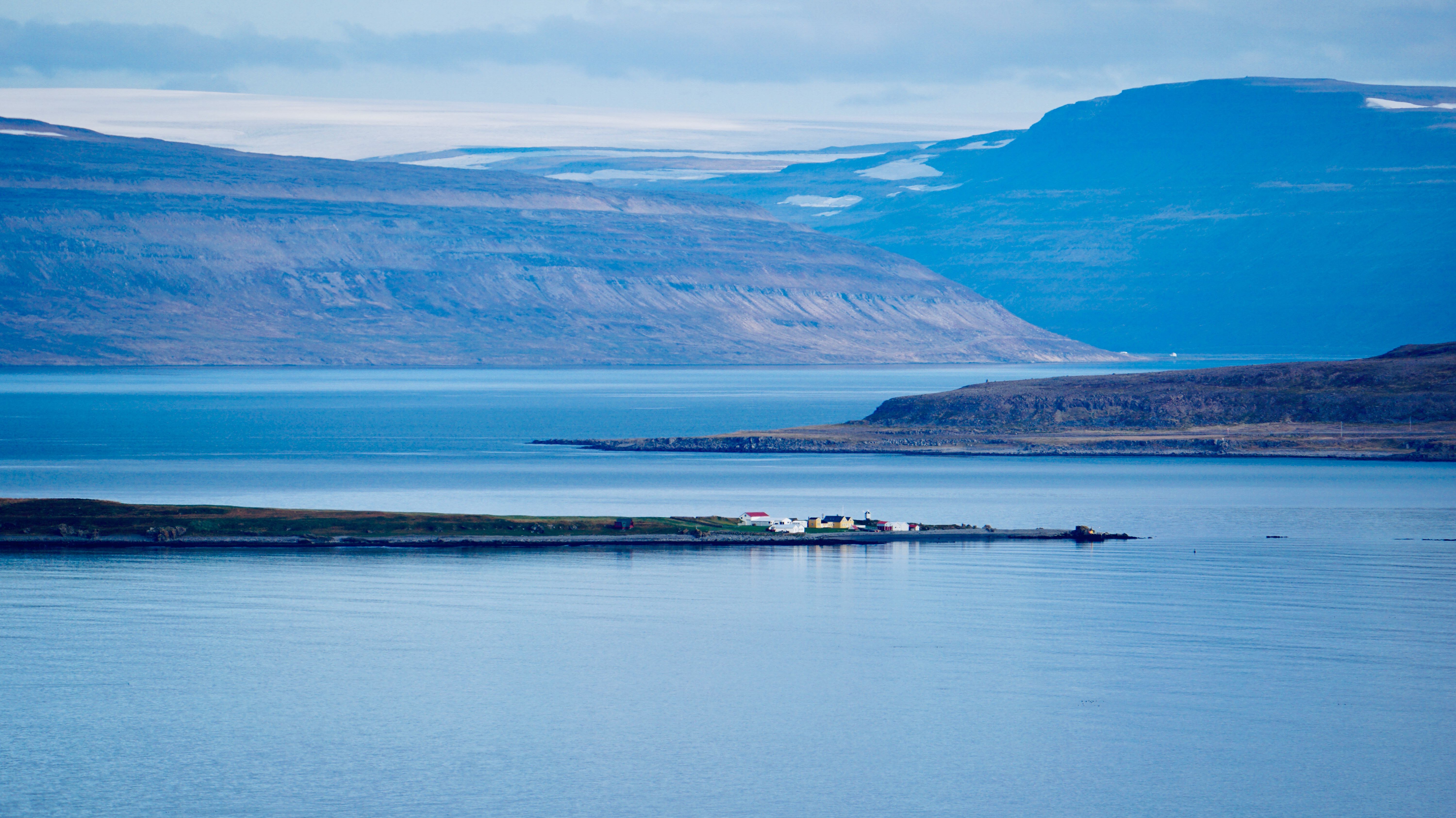 Wide view of a Westfjords fjord below steep flat-topped mountains under low cloud