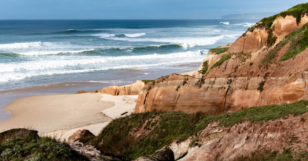 Green hills with traditional round rondavel huts running down to the sea on South Africa's Wild Coast