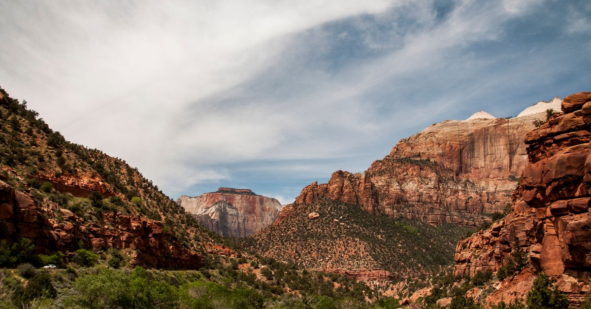 Towering red and cream sandstone walls of Zion Canyon rising above the Virgin River